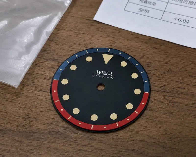 Zwarte prototype wijzerplaat van Wizer met rode en blauwe minutenring